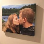 Couple kissing outdoors by a lake with trees in the background, printed as wall art on a gallery canvas.